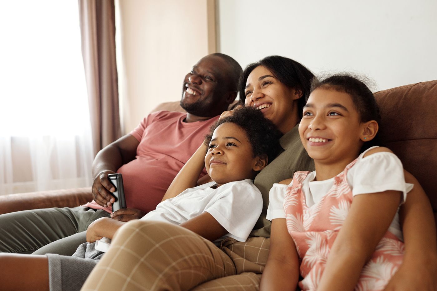 Família sorrindo e compartilhando um momento no sofá de casa — foto de banco de imagens